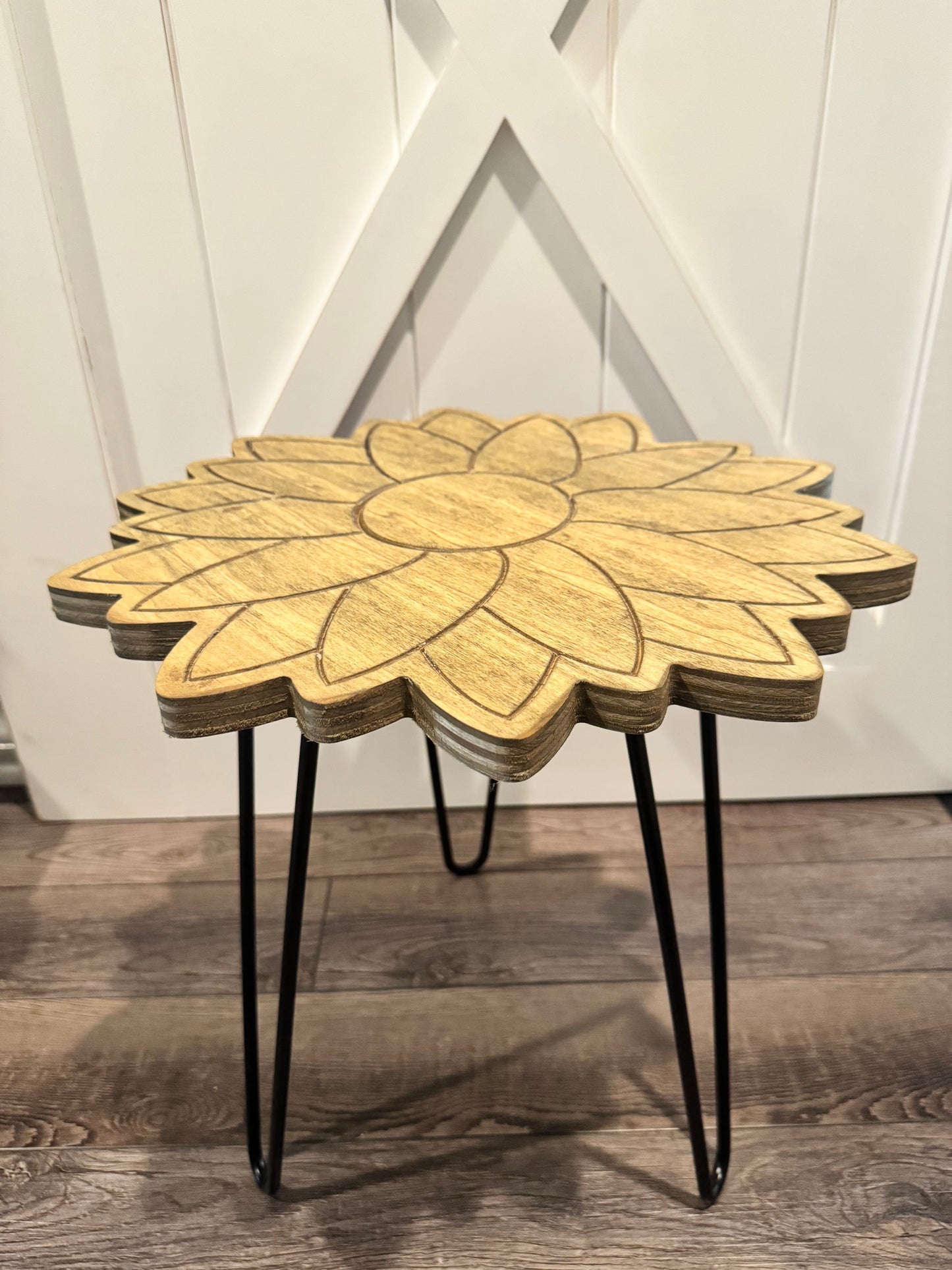 Wood sunflower plant stand with black hairpin legs against a white barn door