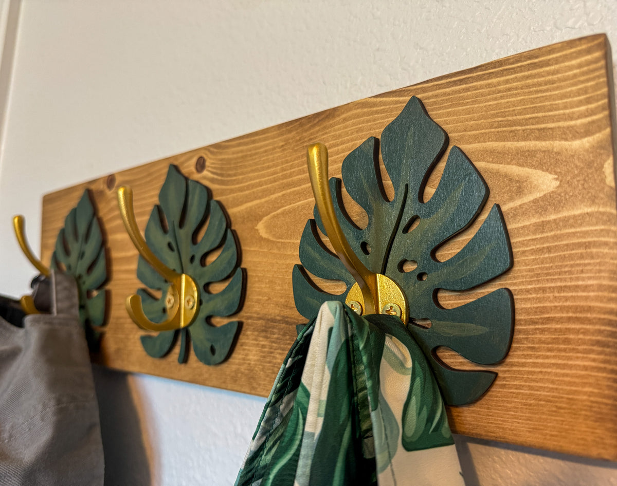 Handcrafted monstera leaf hook rack with gold hooks in espresso stain