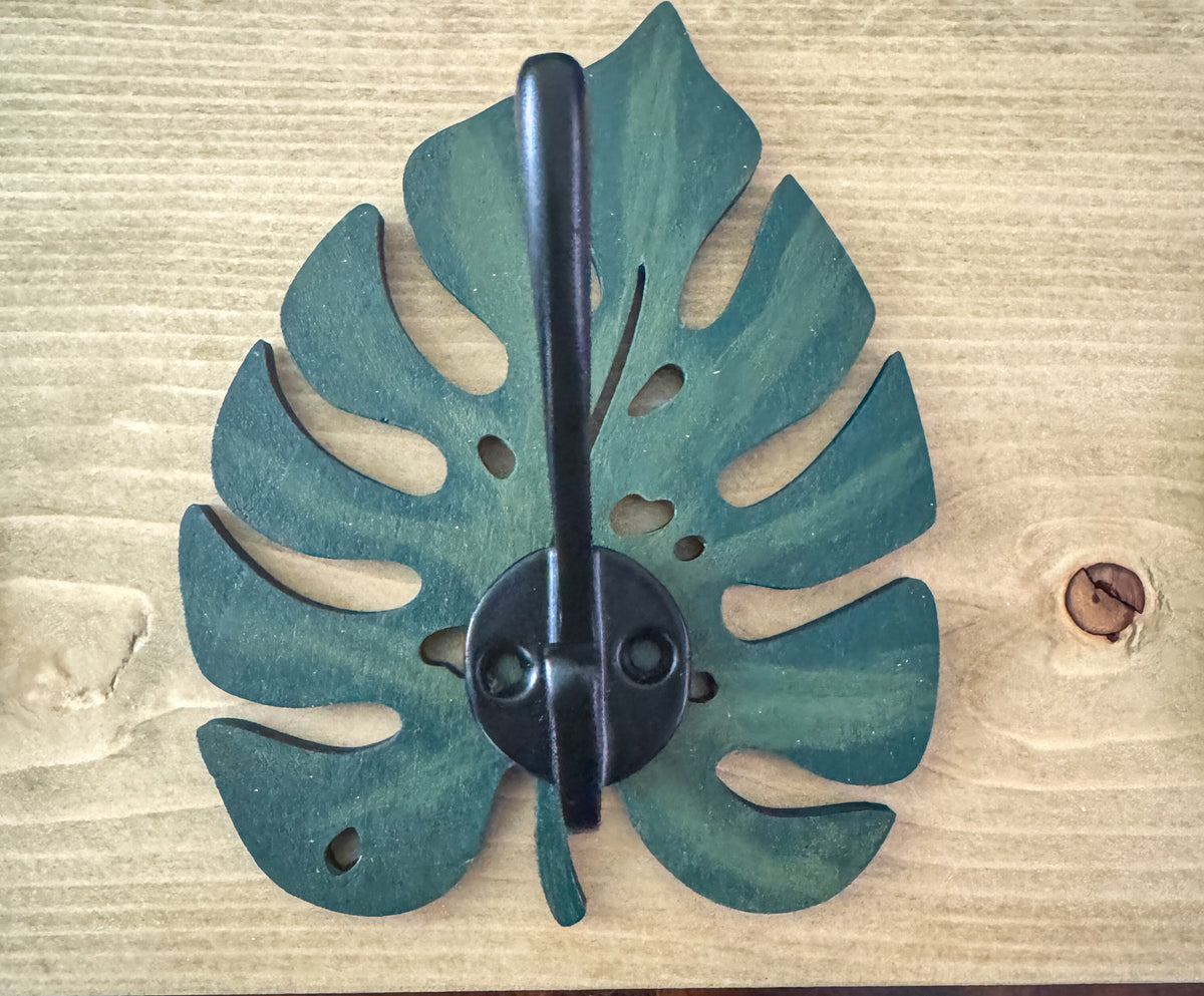 Monstera leaf hook rack with gold hooks holding keys and a bag