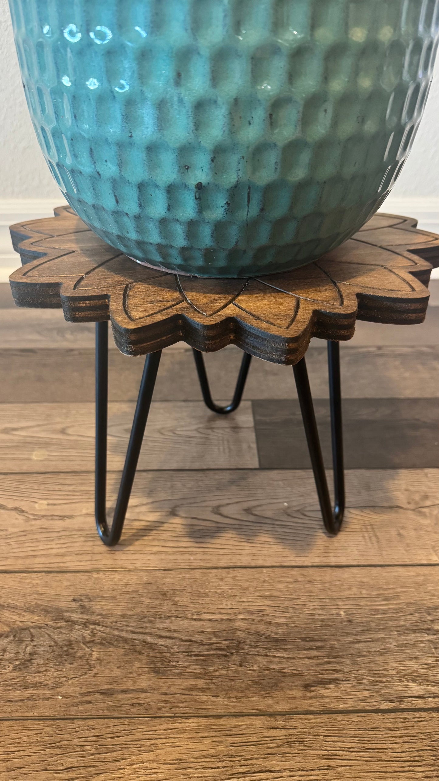 Close-up of the sunflower plant stand's stained wood grain and engraved petals